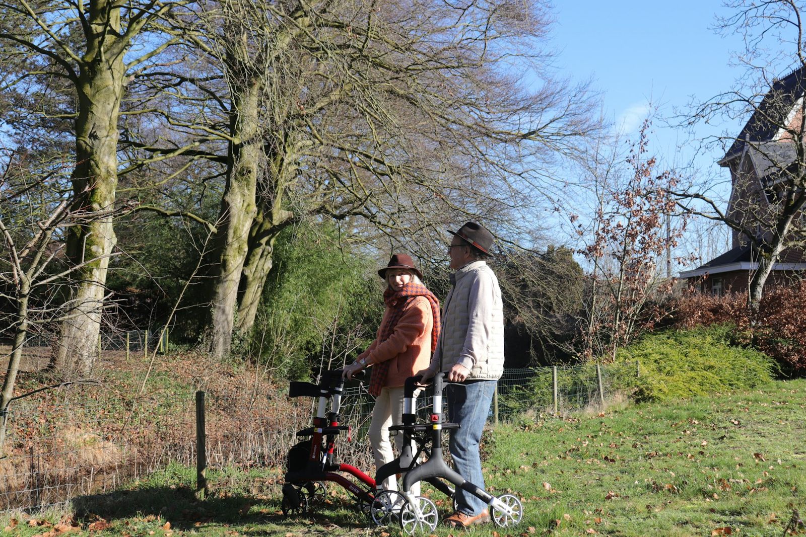 An older couple walking outdoors with rollators