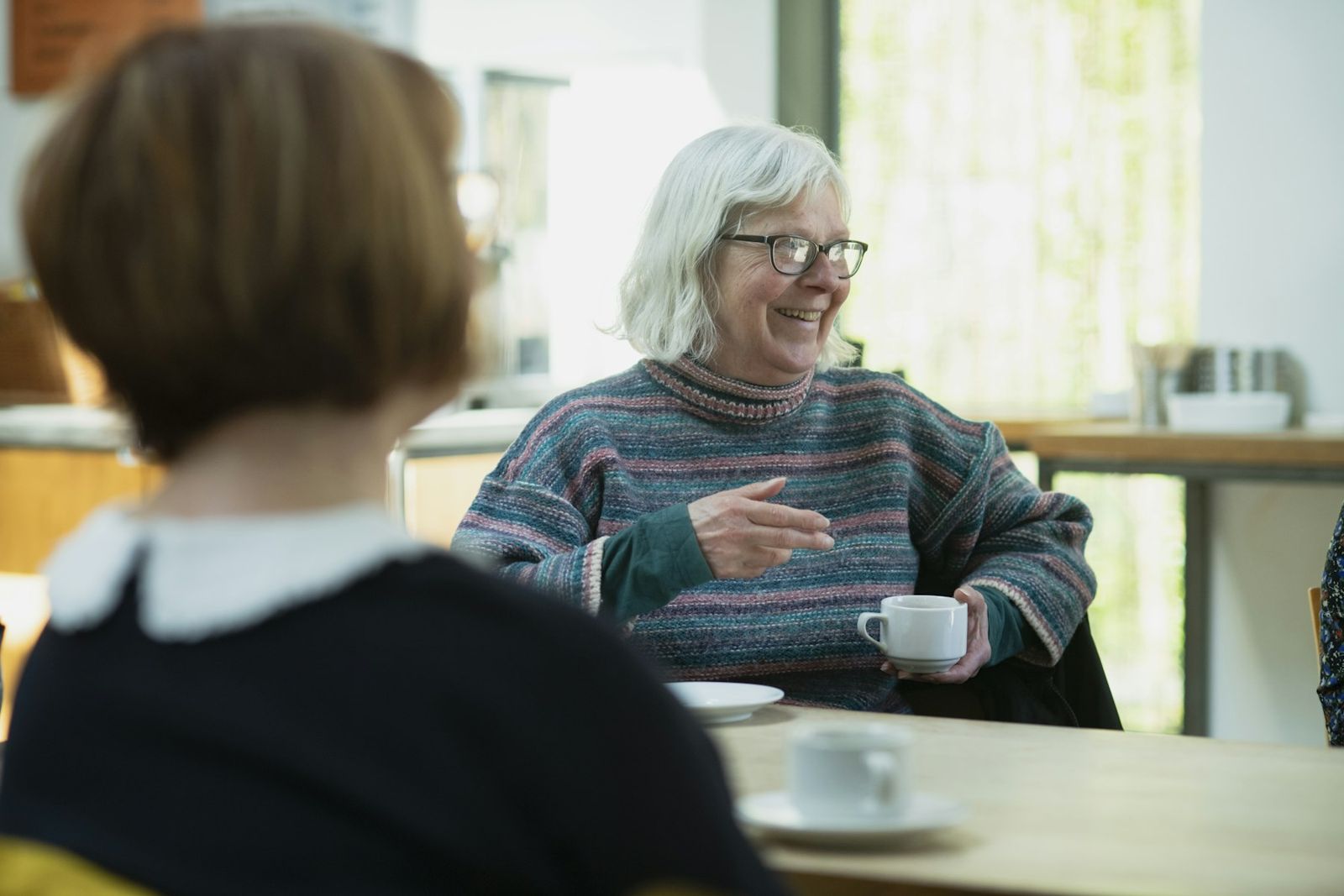 Two people talking across a cafe table