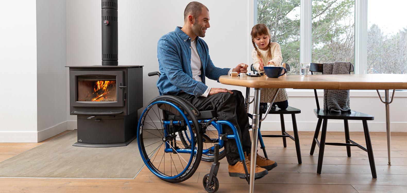 An older man in a folding wheelchair at his dining table at home