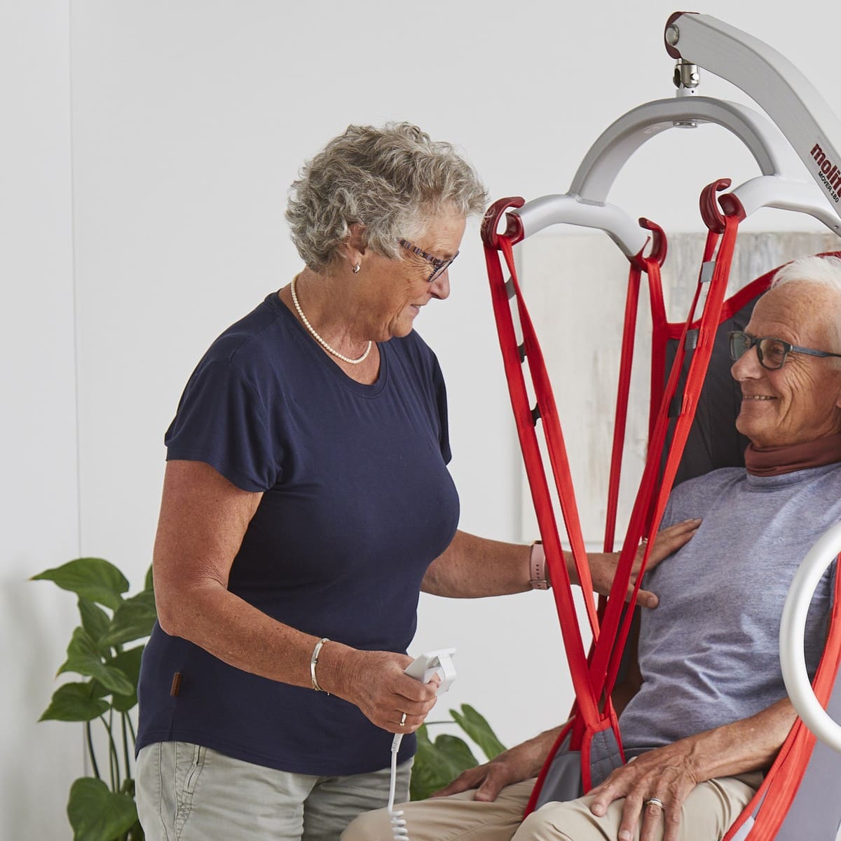 A carer using a Molift mobile hoist and sling to transfer a man at home