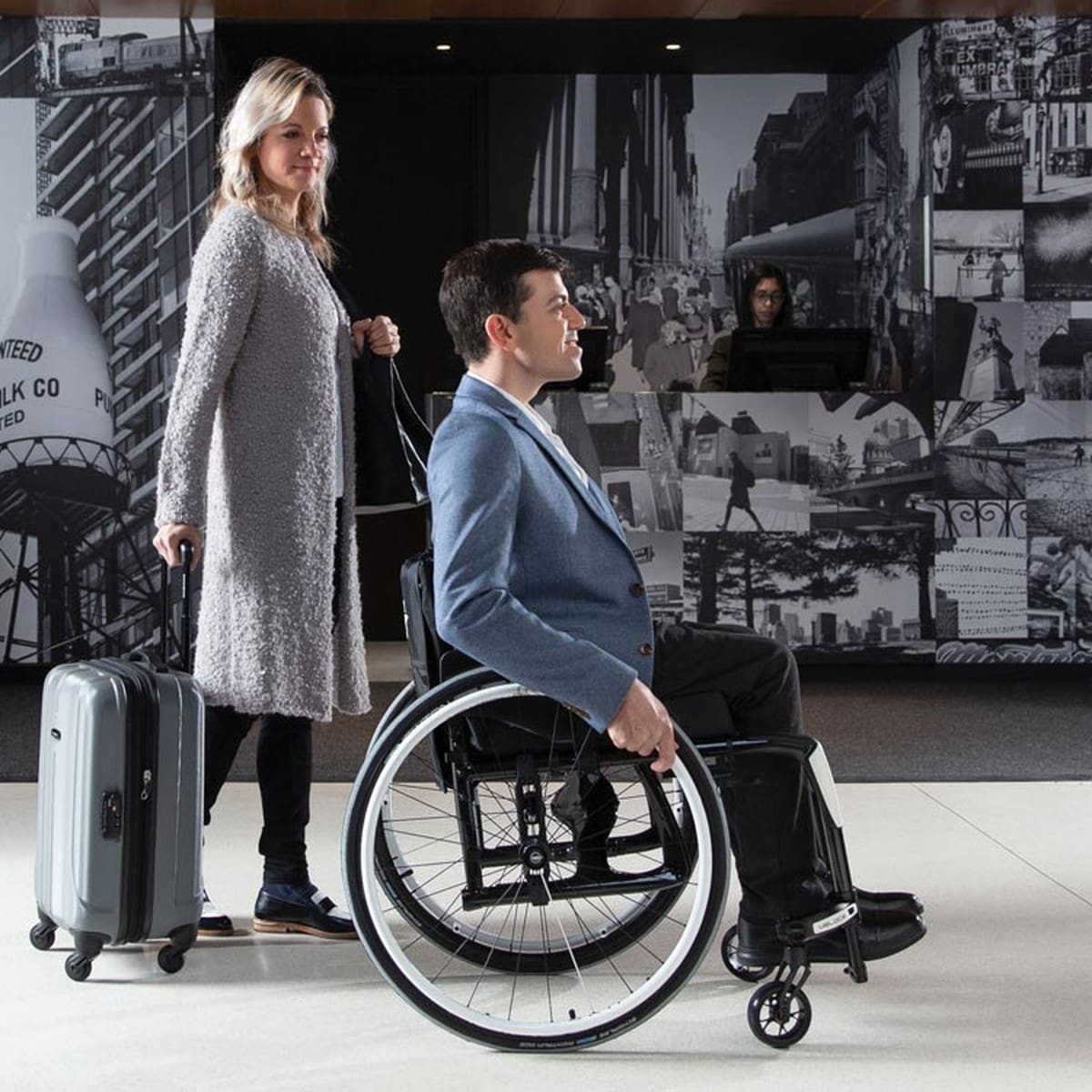 A man using a manual wheelchair, travelling with a companion
