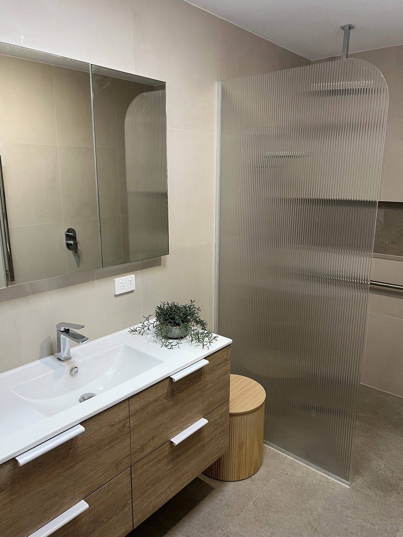 An accessible bathroom with a fluted screen and a rail beside the shower